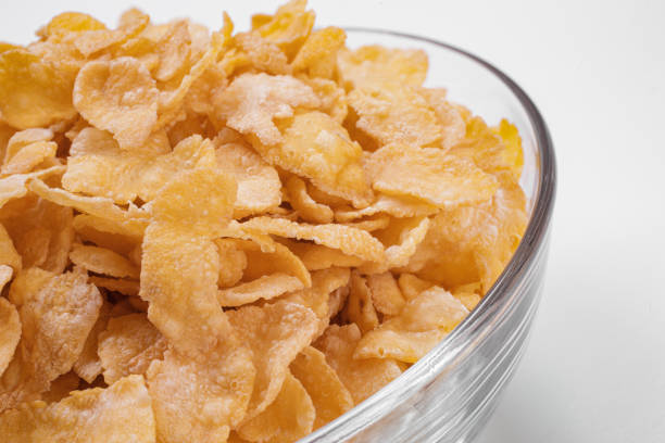 corn flakes inside glass bowl close-up top view on white background
