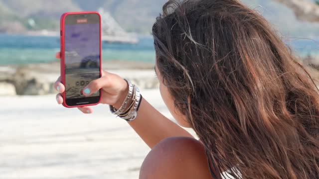 A girl makes a video with her smartphone on a beautiful beach