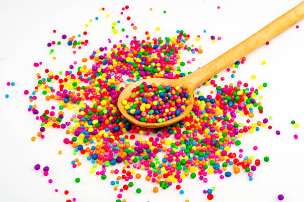 Sugar sprinkles on wooden spoon over white table in the kitchen at home.