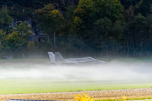 Meiringen Airbase of Swiss Air Force with FA 18 Hornet fighter plane taxiing through fog to cavern hangar on a sunny autumn day. Photo taken October 17th, 2023, Meiringen, Canton Bern, Switzerland.