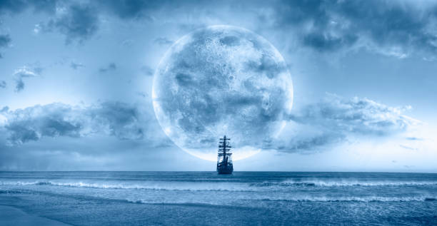 istock Sailing old ship in calm sea - Night sky with moon in the clouds 