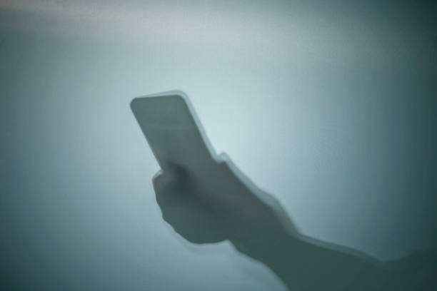 istock Shadow of a human hand holding a mobile phone 1742334364