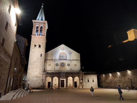 People walking on the square by the Spoleto Cathedral by night, the principal church of Spoleto, an ancient town in Umbria, Italy.