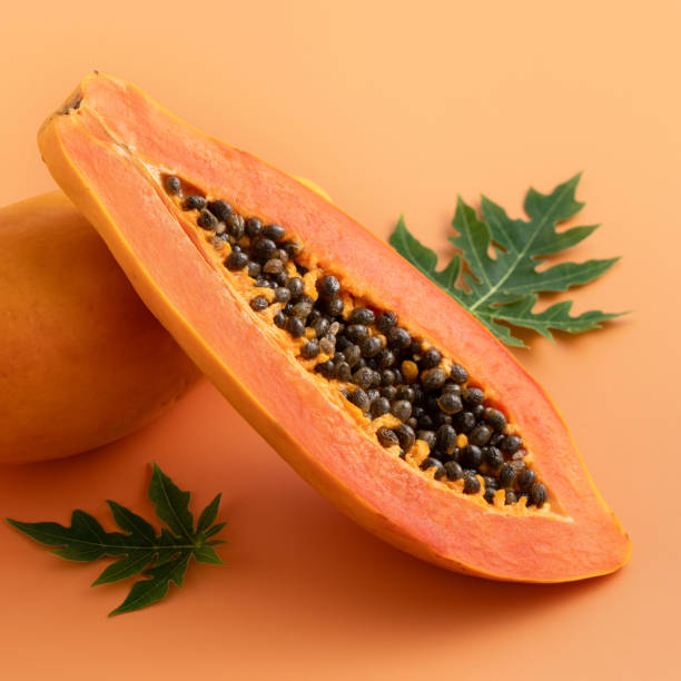 istock Fresh tropical cut papaya fruit over orange table background. 1742356921
