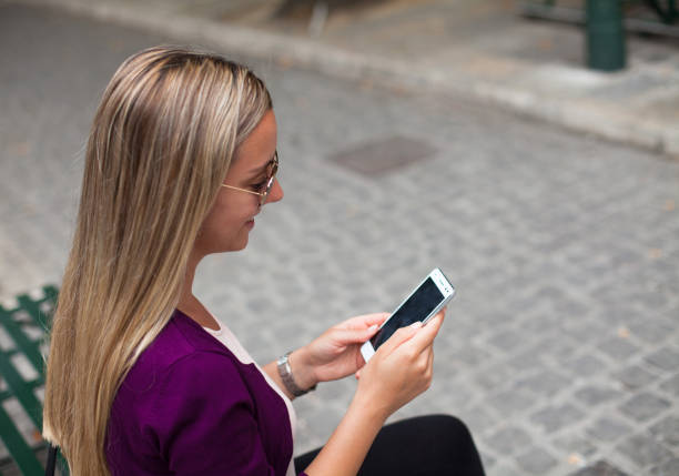 Fashion young woman using her smartphone in city