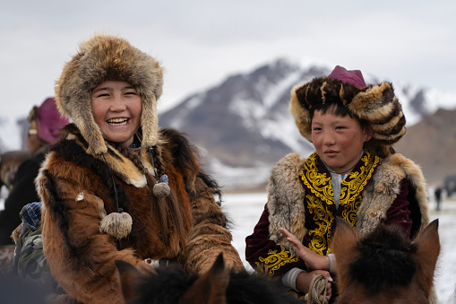 Bayan-Olgii Province, Mongolia - October 1, 2023: Teenager Aimuldir D., an ethnic Kazakh female eagle hunter and eventual winner of the Ulgii Golden Eagle Festival, shares a laugh with a friend.