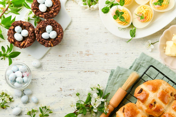 istock Easter brunch or breakfast. Easter chocolate nest cake with chocolate candy eggs, traditional hot cross buns and deviled eggs with bouquets of blooming apple trees. Spring Easter holiday food concept. 1742374213