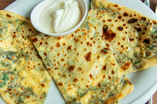 Delicious gourmet flat bread kutabs with herbs and cheese on a plate
