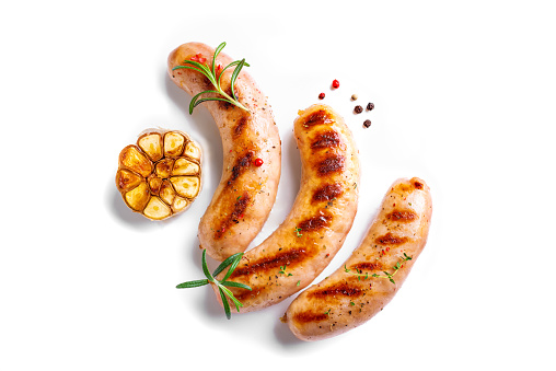 Grilled sausages with garlic and rosemary isolated on white background, top view, copy space. Roasted homemade wurst sausages.