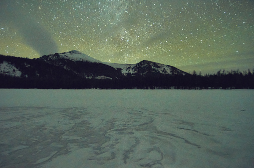 Snow-covered winter mountain lake, Russia, Siberia, Altai mountains. Multinskie lakes. Starry night on a frozen winter mountain lake.