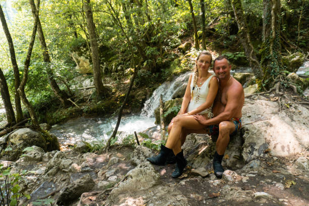 istock Happy couple sitting at riverbank and looking at camera 1742389598