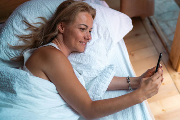 istock Happy woman lying in the bed and using mobile phone 1742391882