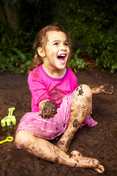 Little girl playing in the mud and water outside