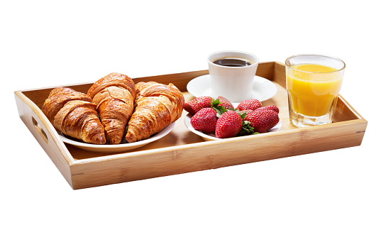 Food, croissants, coffee, orange juice Strawberries served in a wooden tray on a white background.