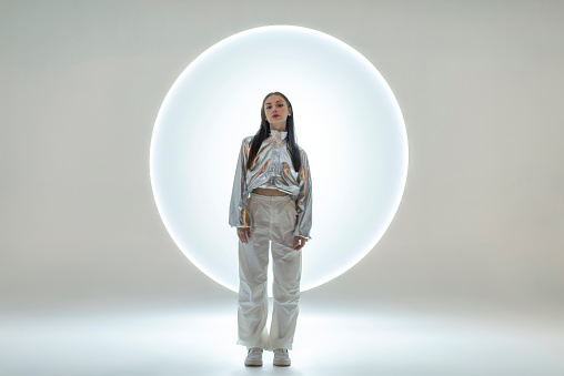 Young woman in front of a circular light shape.