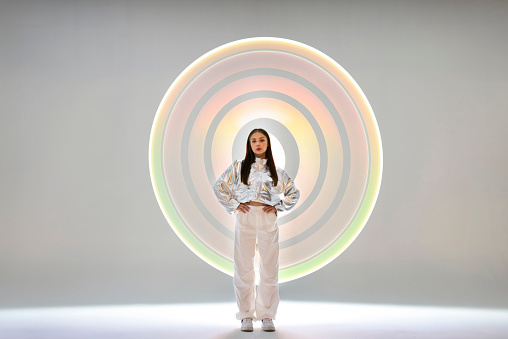 Young woman in front of a circular light shape.