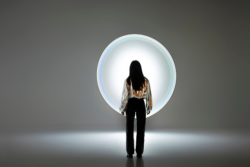 Young woman in front of a circular light shape.