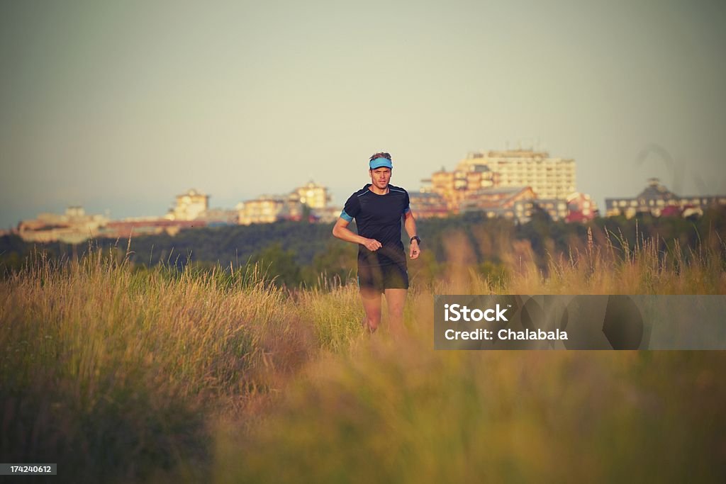 Running Young man is running on summer meadow - lovely sunset light Achievement Stock Photo