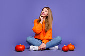 Full length shot of minded teen schoolgirl look empty space with pumpkins preparing make jack lantern isolated on purple color background