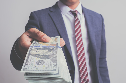 closeup businessman in suit holding one hundred 100 dollar bill. money concept