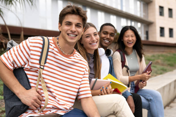 istock Diverse people smiling sitting outside holding folders. Multicultural group of happy students looking at camera with backpacks and notebooks. 1742427443