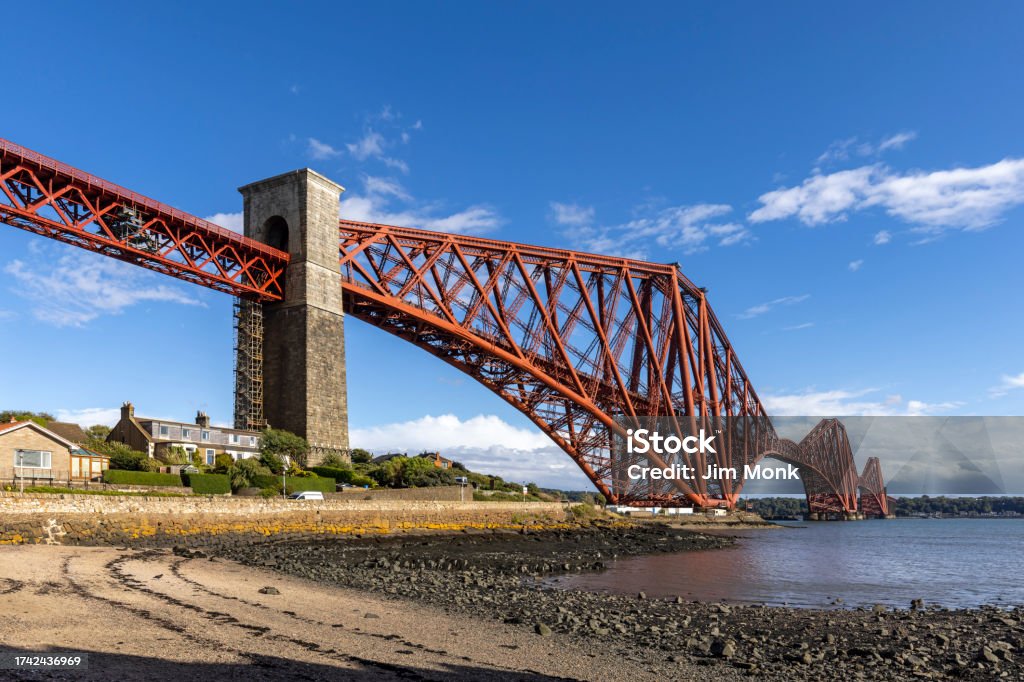 Forth Rail Bridge, North Queensferry The mighty Forth rail bridge spreading across the Firth of Forth connecting north and south Queensferry. Taken from North Queensferry on A bright summer's day. Arch - Architectural Feature Stock Photo