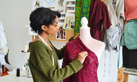 A young fashion designer adjusting her designs in her studio