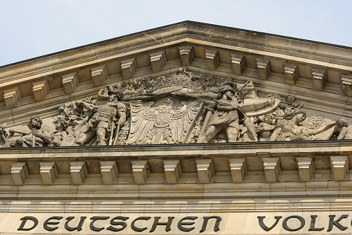 Berlin, Germany - 4 July 2010: Exterior of Reichstag building with in summer blue sky background. Close up detail of sculpture and inscription Dem Deutschen Volke (To the German People). No people.
