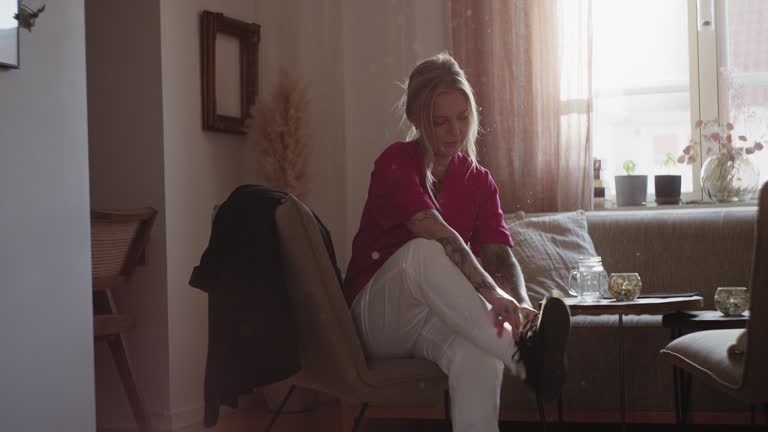 Woman preparing to leave her apartment, tying her shoes