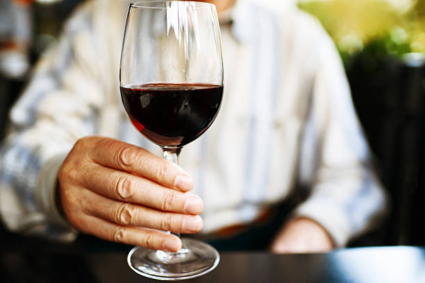 senior hombre que agarra copa de vino tinto en el café al aire libre - wine degustation winetasting cafe fotografías e imágenes de stock