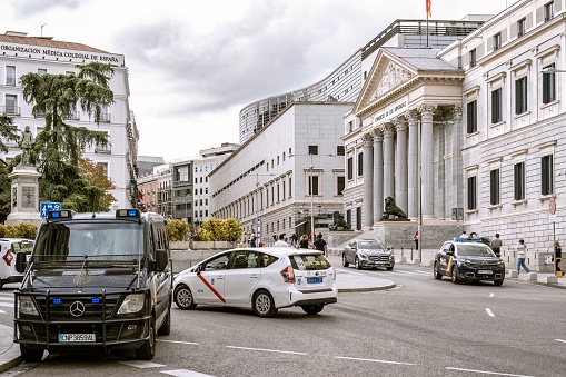 Madrid, Spain; 10-16-2023: Calle or Carrera de San Jeronimo and facade of the Congress of Deputies, headquarters of the Spanish parliament on a cloudy day guarded by a police van nearby