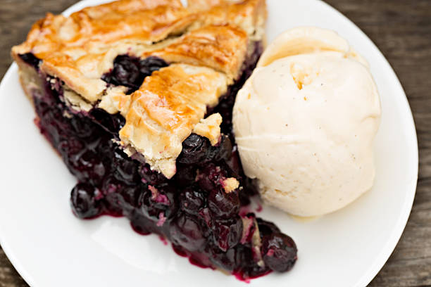Homemade sweet sour cherry pie with vanilla ice cream, rustic wooden background copy space