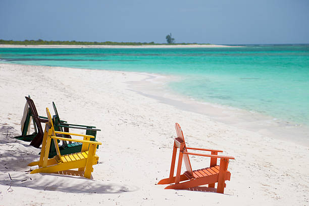 empty colorful chairs at a tropical beach in Anegada, BVI group of empty colorful adirondack chairs at a tropical beach in Anegada, British Virgin Islands beautiful multi colored tranquil scene enjoyment stock pictures, royalty-free photos & images