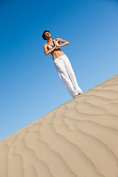 istock Woman meditating on sand dune 174250684
