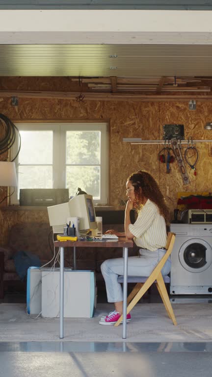 Vertical Screen: Hispanic Female Developer Programming On Old Desktop Computer In Retro Garage With Random Appliances. Young Woman Working On Innovative Online Service Startup Company In Nineties.