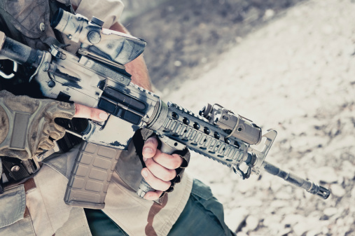 Close up of a contractor soldier holding an assault M4 rifle with finger off the trigger.
