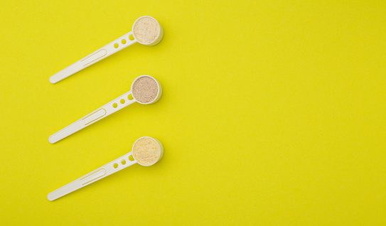 Spoons with different dairy-free cereals for children on a yellow background. Rice, wheat and buckwheat porridge for feeding babies. Copy space for text, bifidobacteria