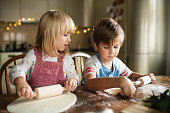 Children rolling up dough for a cake or pizza at the kitchen