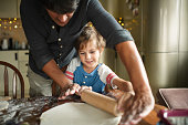 Family rolling up dough for cake or pizza at the kitchen