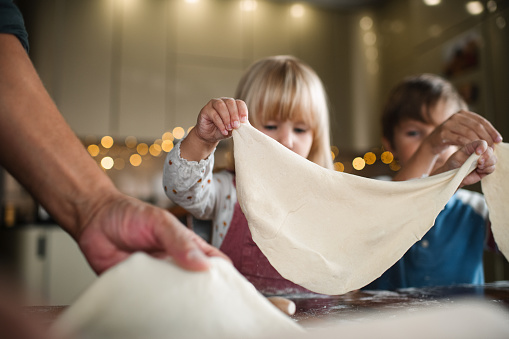 Happy loving family are preparing bakery together. Mother and child daughter girl are cooking cookies and having fun in the kitchen. Homemade food and little helper.