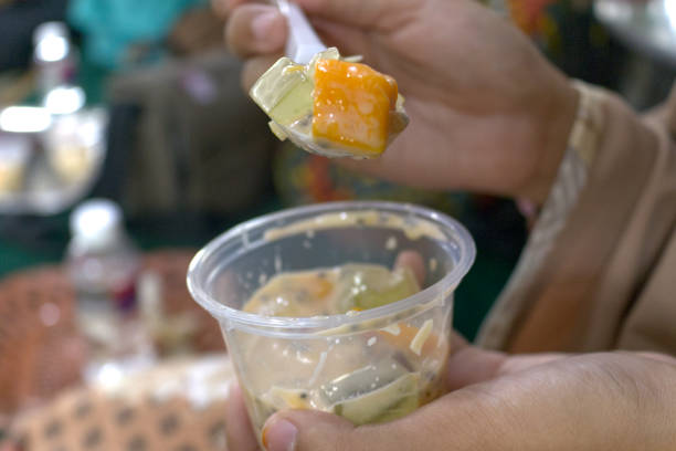 istock Asian child's hand is scooping fruit salad with a plastic spoon from its container 1742573730