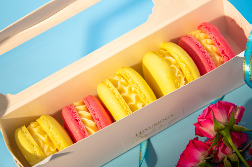 Colored macaroons in a package on a blue background close-up