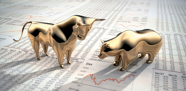Golden bull and bear figurines on stock market newspaper - 3D illustration