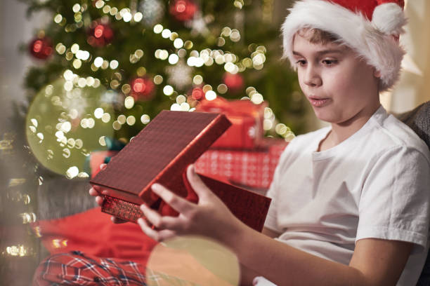 istock Joyful boy in a Santa hat opens a Christmas present. Boxing day. Christmas Eve Magic night 1742599363