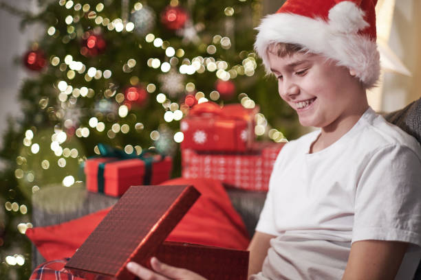 istock Joyful boy in a Santa hat opens a Christmas present. Boxing day. Christmas Eve Magic night 1742599435