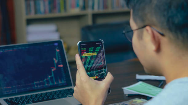 istock Asian man using phone analyzing Crypto Graph On Laptop at home. 1742612679