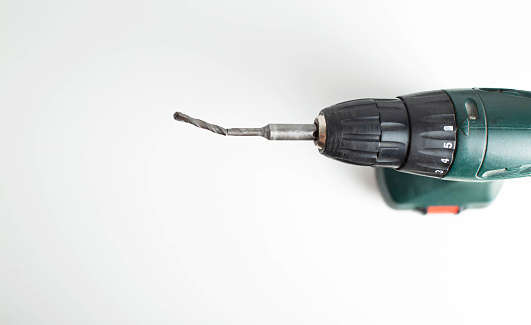 Broken low-quality drill in a screwdriver on a white background, close-up