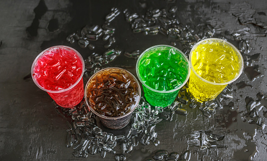 Top view of A lot of Soft drinks in colorful and flavorful glasses on the black background, Soft drinks or Carbonated beverages on ice