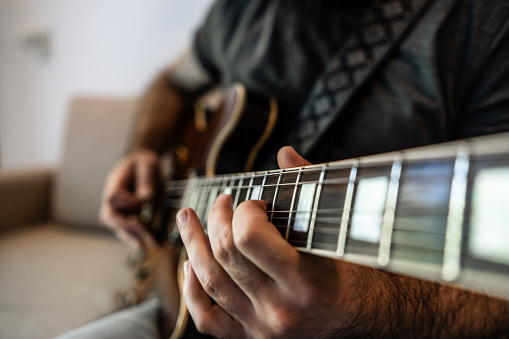 Close-up of a man playing guitar at home