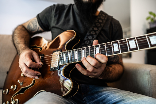 Close-up of a man playing guitar at home